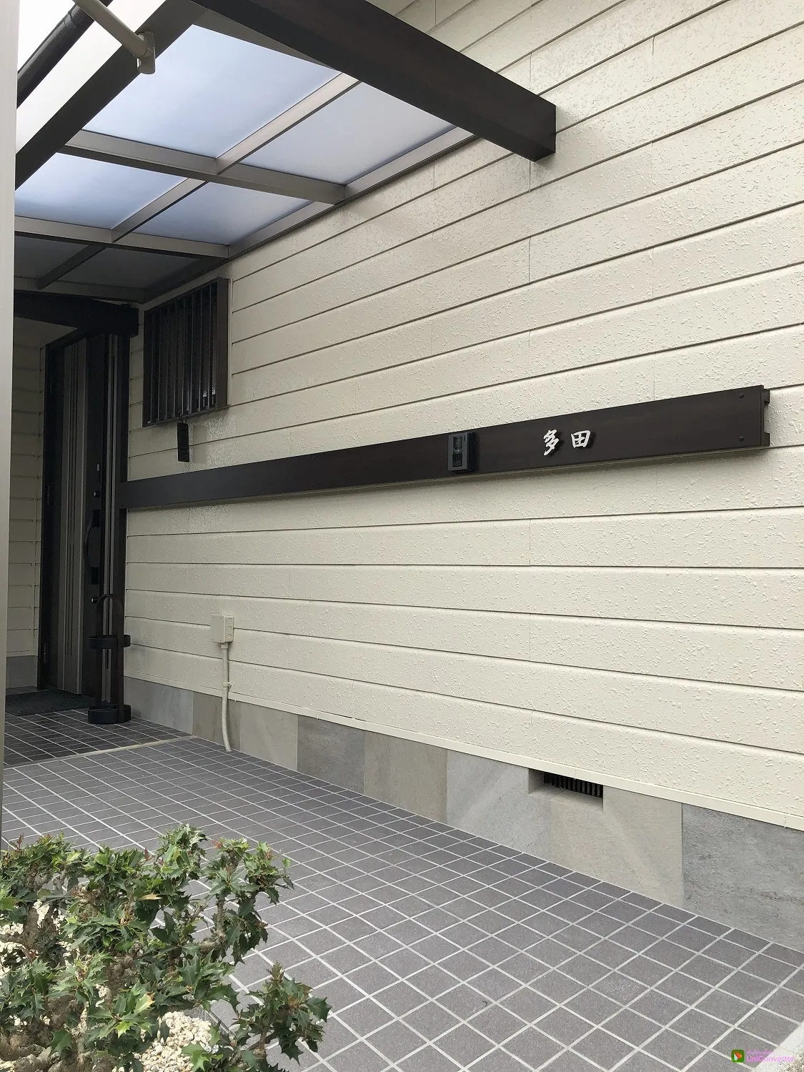 水平方向にのびる外壁目地に合わせた木目調のアルミ平版が玄関周りを演出します