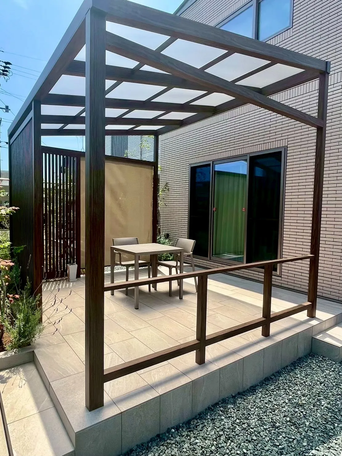 シェード付きの木調パーゴラとタイルテラスからなる上質なアウトドア空間