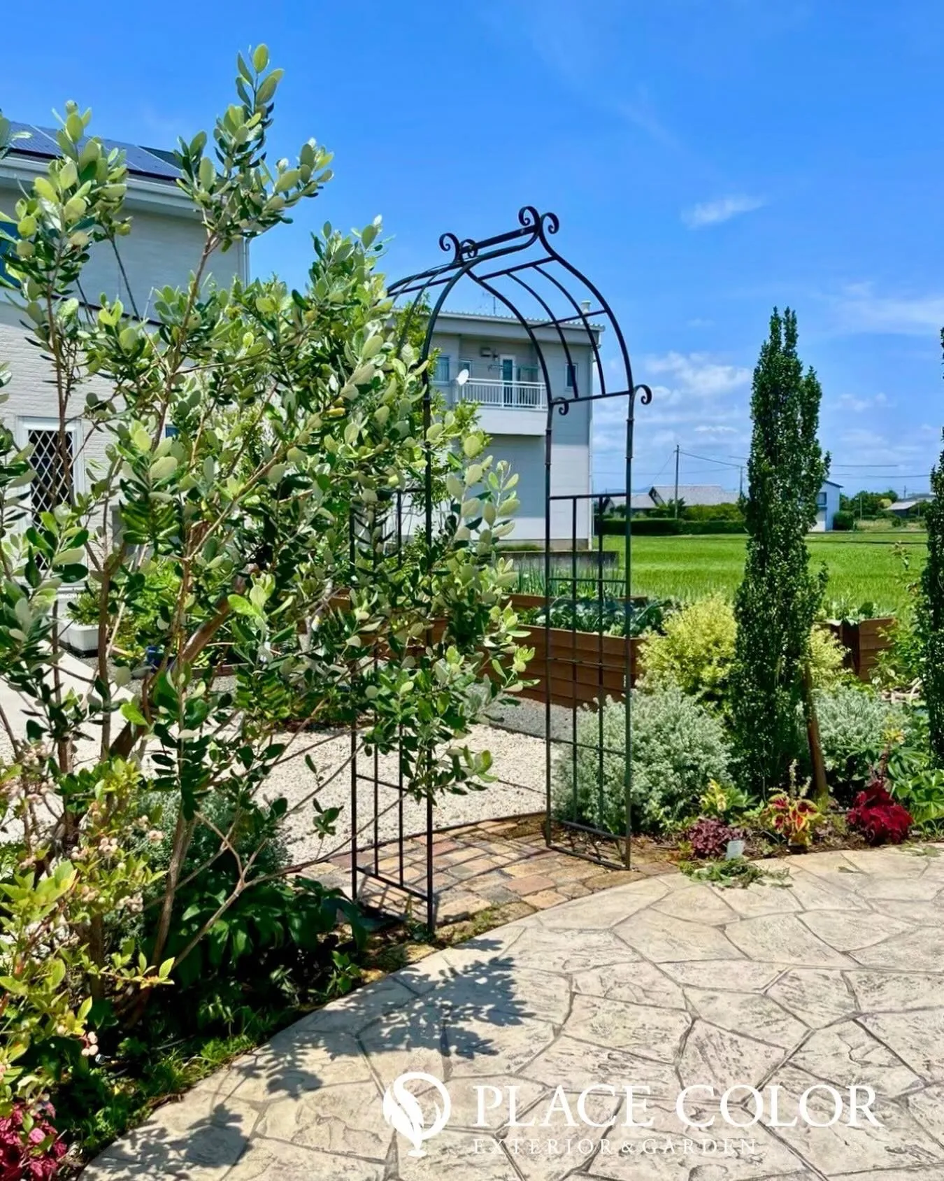 アイアンのアーチが迎えるアプローチと、サークル状の舗装が印象...