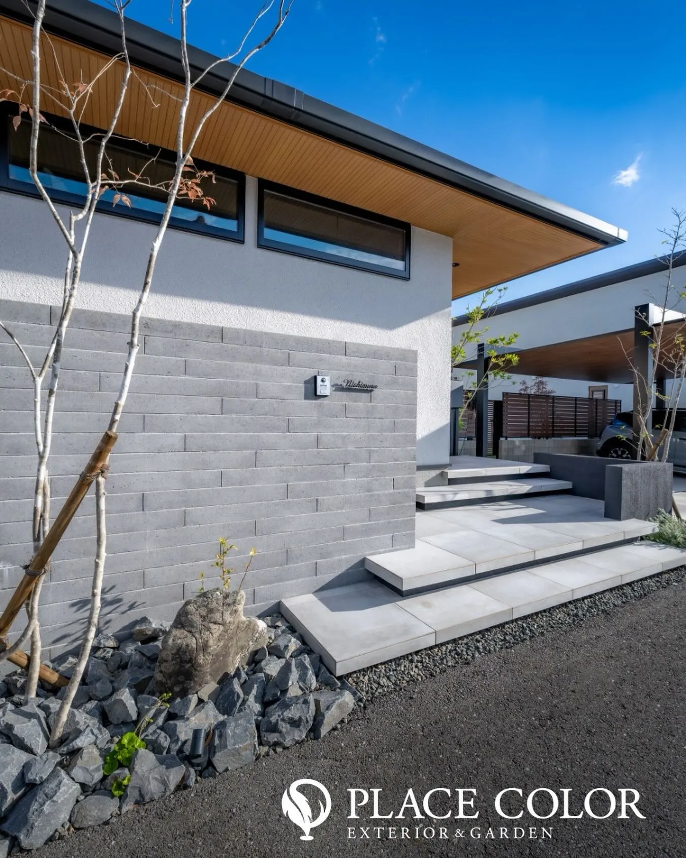 グレーのタイルと塀が調和し、直線的な美しさが際立つアプローチ...