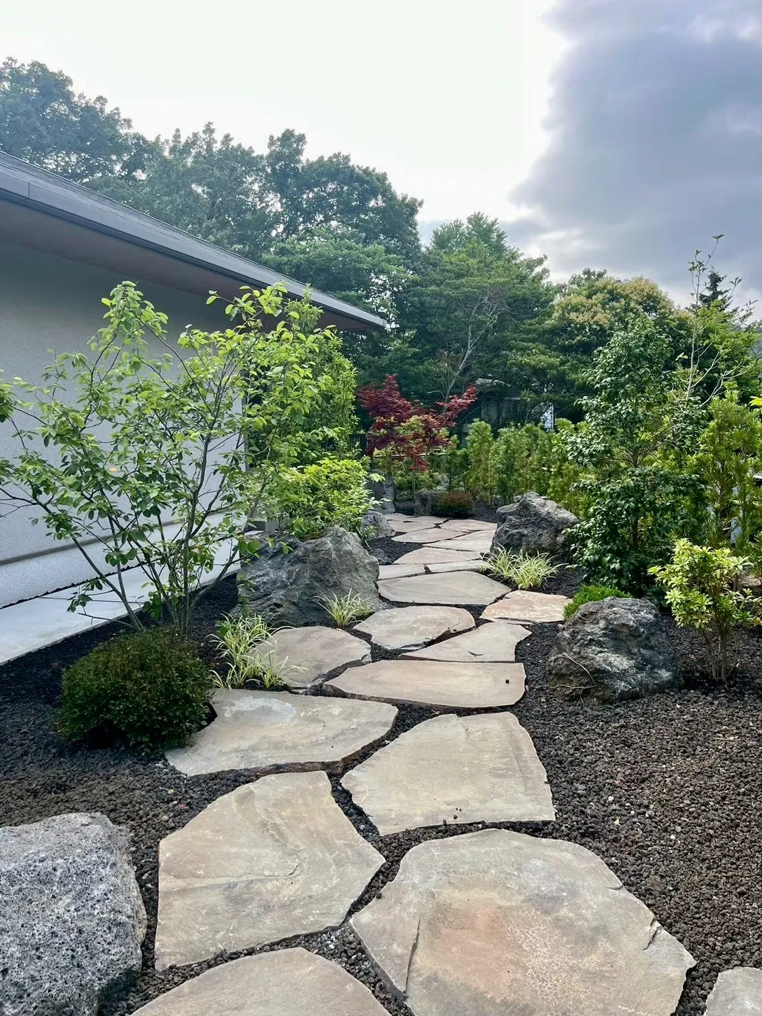 自然石を敷き並べた緑豊かな庭へと誘う和のアプローチ