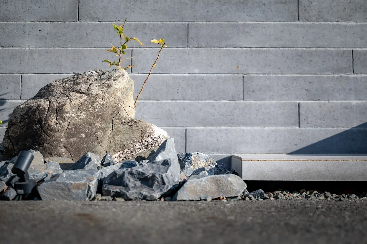 景石の力強さと小さな芽吹きが、時間の流れと住まいの物語を感じさせる足元のデザインです