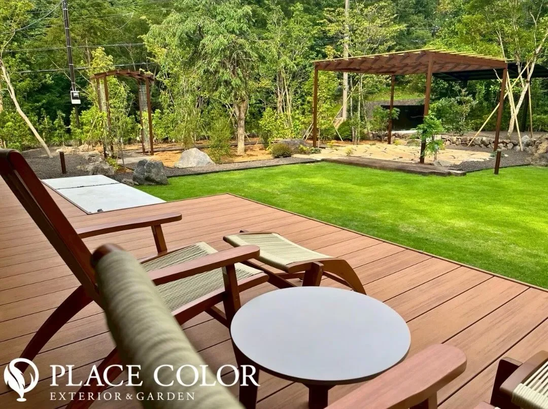 ウッドデッキから広がる芝生と、木々に囲まれた落ち着きある庭 ...