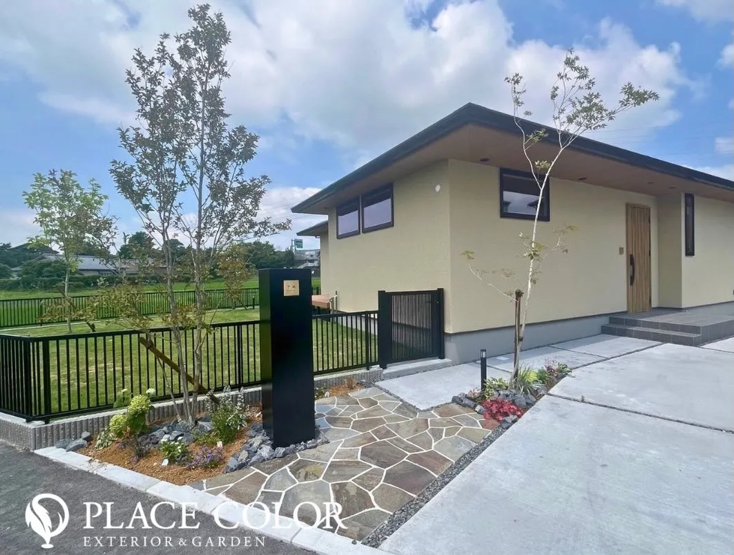 ブラックの門柱とフェンスが外観を引き締め、石貼りのアプローチ...